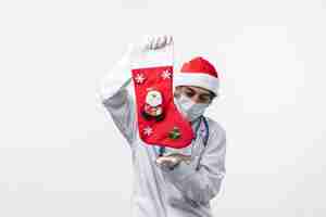 Free photo front view male doctor holding red sock on white wall covid- christmas virus health