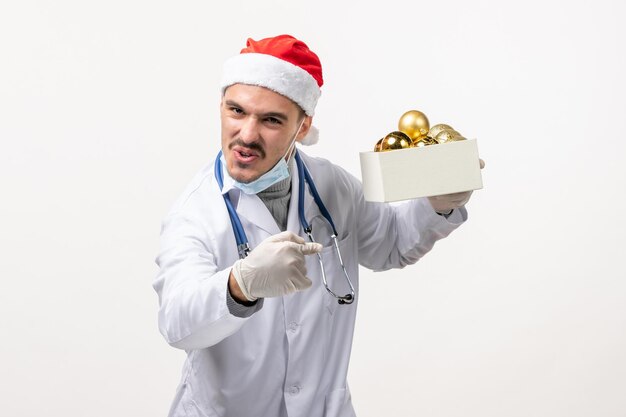 Front view of male doctor holding toys on the white wall