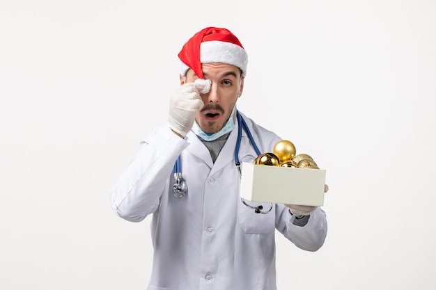 Front view of male doctor holding toys on white wall