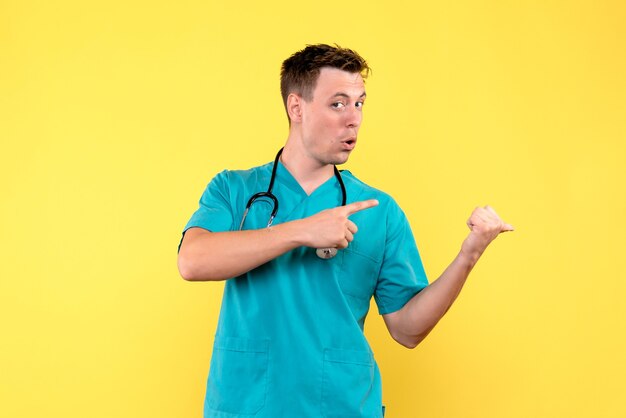 Front view of male doctor just standing on yellow wall