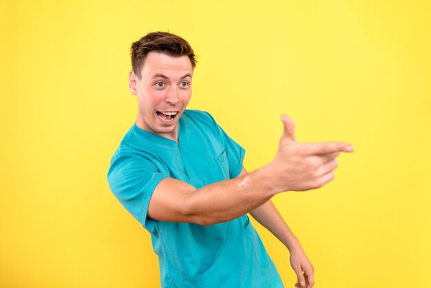 Front view of male doctor just standing on yellow wall