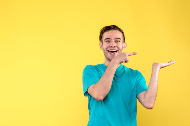 Front view of male doctor laughing on yellow wall