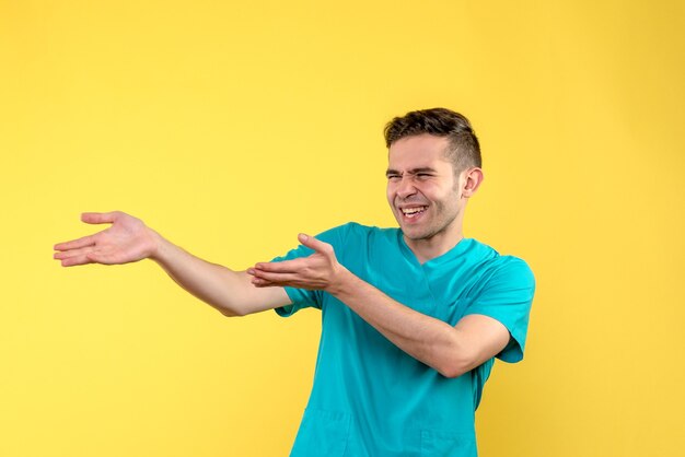 Front view of male doctor laughing on yellow wall