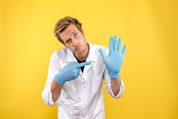 Вид спереди мужской доктор на светло-желтом фоне медик covid- гигиена здоровья