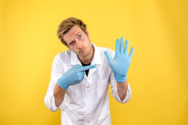 Front view male doctor on light yellow background medic covid- health hygiene