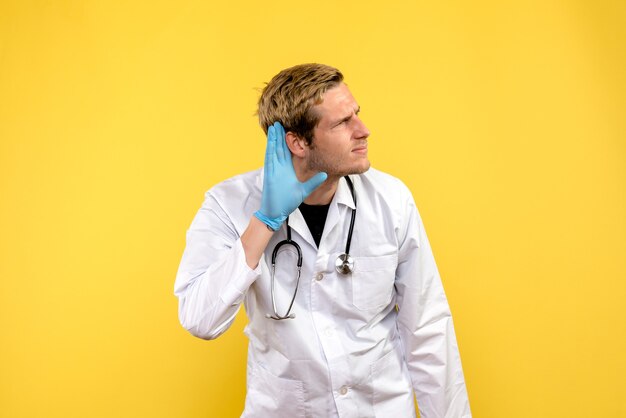 Front view male doctor listening on yellow background health medic human virus