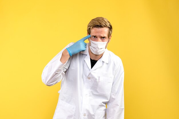 黄色の背景の健康covidウイルスパンデミックを見ている正面図男性医師