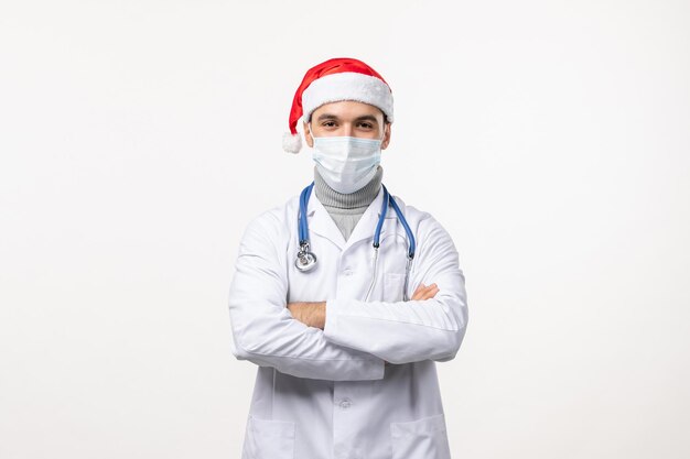 Front view of male doctor in mask on a white wall