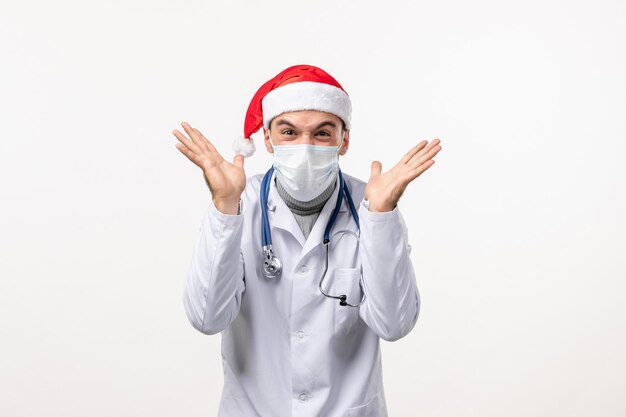 Front view of male doctor in mask on a white wall