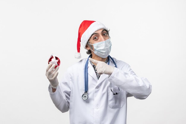 Front view male doctor in mask with toy on white desk health covid holiday virus