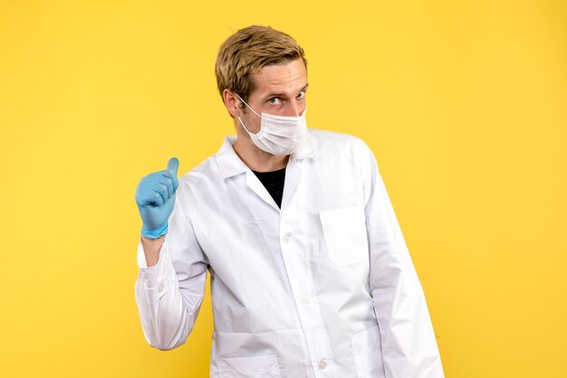 Front view male doctor in mask on yellow background covid pandemic health medic