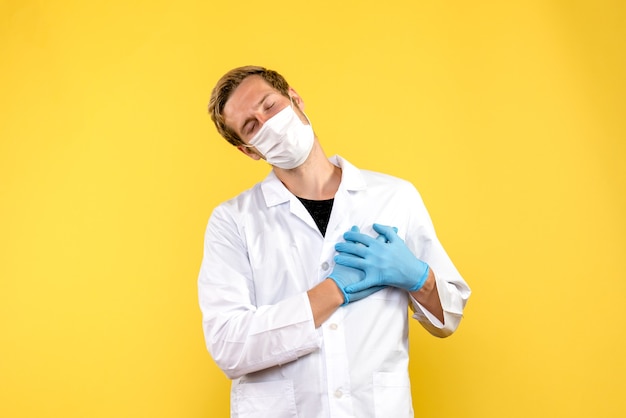 Front view male doctor in mask on yellow background health covid medic pandemic