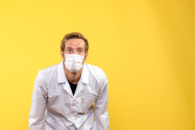 Front view male doctor in mask on yellow background pandemic covid- health virus