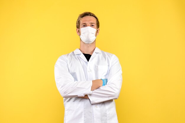 Front view male doctor in mask on yellow background virus health covid- pandemic