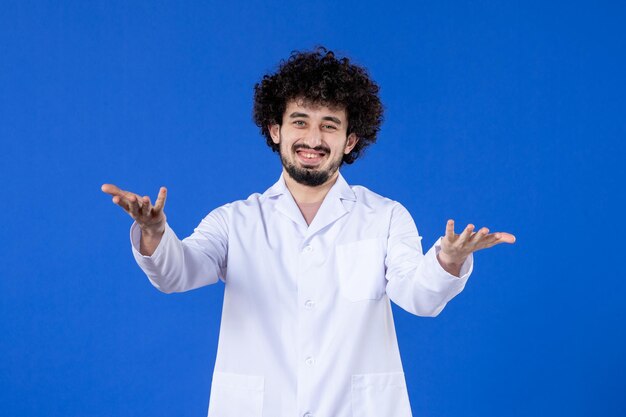 Front view of male doctor in medical suit on blue background vaccine virus covid- pandemic drug hospital coronavirus health medicine