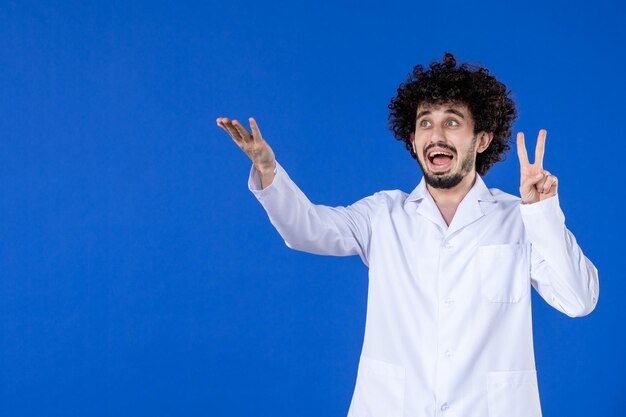 Front view of male doctor in medical suit on blue surface