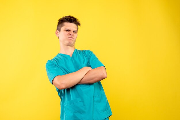 Front view of male doctor in medical suit displeased on yellow wall