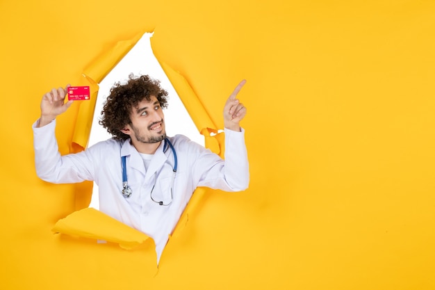 黄色の薬病院病ウイルス薬のお金の健康に赤い銀行カードを保持している医療スーツの正面図男性医師
