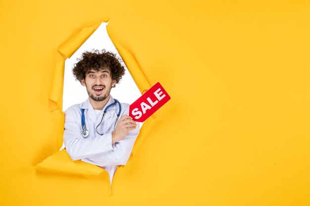 Front view male doctor in medical suit holding red sale writing on a yellow medic color virus medicine money health hospital disease