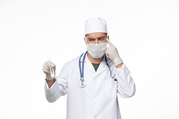 医療スーツを着た正面図の男性医師とホワイトデスクウイルス感染症パンデミックのコロナウイルス保持装置に対するマスク