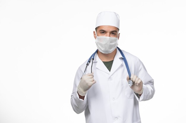 흰 벽에 코로나 바이러스에 대한 의료 소송 및 마스크의 전면보기 남성 의사 covid- disease 질병 격리 전염병