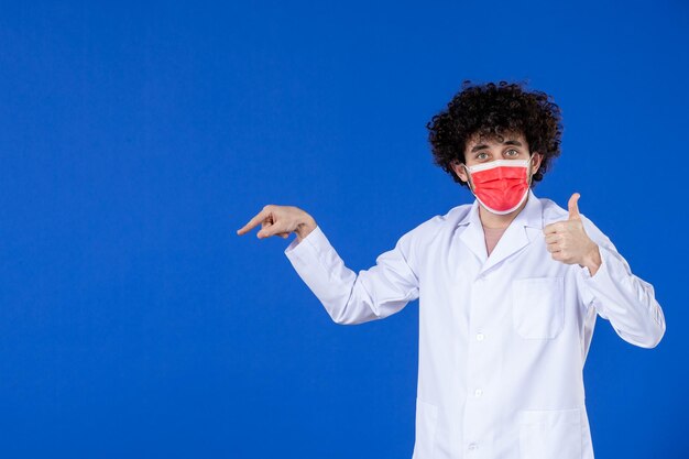 医療スーツを着た男性医師の正面図と青い背景のマスク病院コビッドウイルスパンデミックコロナウイルス薬の健康