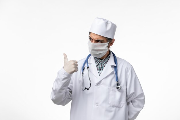 밝은 흰색 표면에 코로나 바이러스로 인해 의료 복과 마스크의 전면보기 남성 의사
