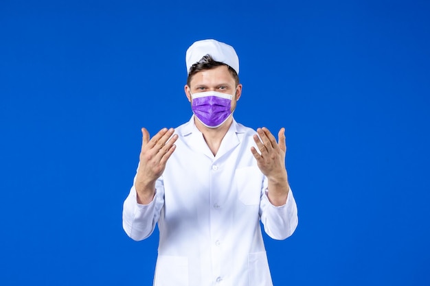 Vista frontale del medico maschio in tuta medica e maschera viola sull'azzurro