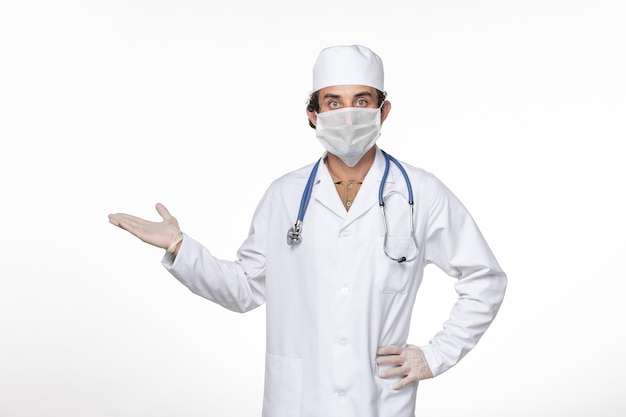 흰 벽에 코로나 바이러스에 대한 그의 마스크를 쓰고 의료 소송에서 전면보기 남성 의사 코로나 바이러스 바이러스 대유행 의학