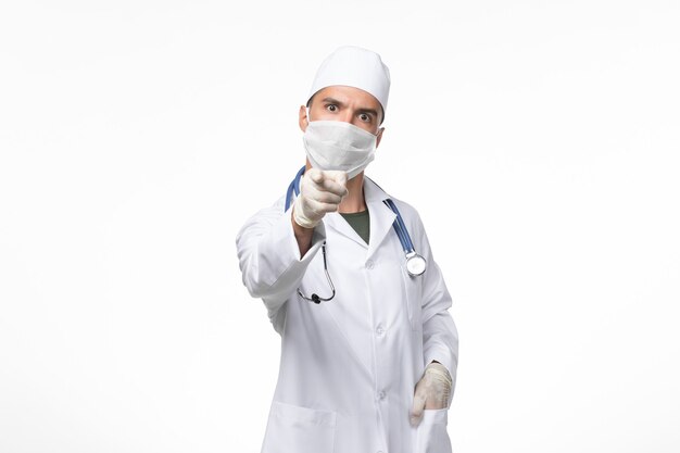 의료 소송에서 전면보기 남성 의사와 흰 벽에 코 비드에 대한 마스크를 착용 covid 질병 질병 유행성 바이러스