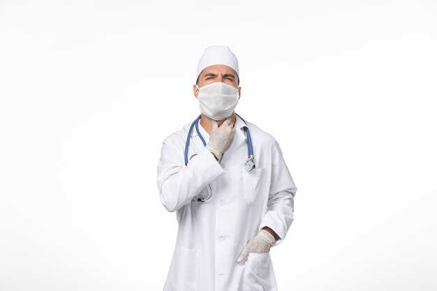 医療スーツを着て、白い机の上のcovidに対してマスクを身に着けている正面図男性医師covidウイルス医学パンデミック