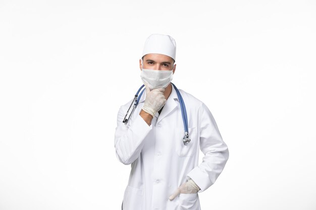 의료 소송에서 전면보기 남성 의사와 흰 벽 covid- 질병 질병 유행성 바이러스에 파란색 청진 생각과 covid에 대한 마스크를 착용