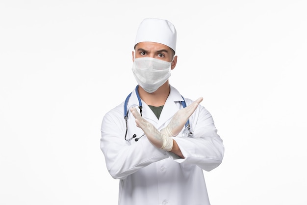 의료 소송에서 전면보기 남성 의사와 흰색 책상 바이러스 covid- 질병 전염병에 청진기로 covid에 대한 마스크를 착용
