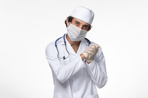 의료 복을 입은 남성 의사와 흰색 책상 질병 바이러스 covid- 전염병으로부터 보호하기 위해 마스크를 쓰고있는 전면보기