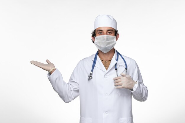 白壁ウイルス病の健康コロナウイルス感染からの保護としてマスクを身に着けている医療スーツの正面図男性医師