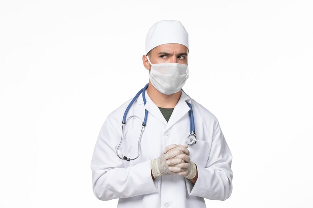 Вид спереди мужчина-врач в медицинском костюме и в маске из-за вируса covid - на стене белого света - covid - пандемического вируса