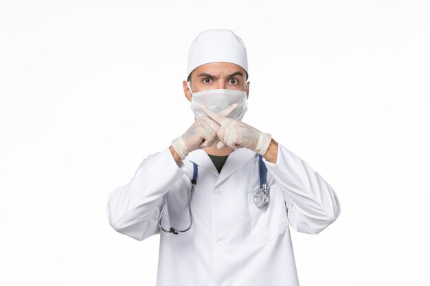 흰 벽에 코로나 바이러스 질병으로 인해 의료 복을 입은 남성 의사와 마스크 착용 전면보기