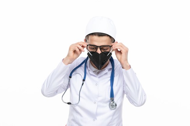 Front view male doctor in medical suit wearing special black mask