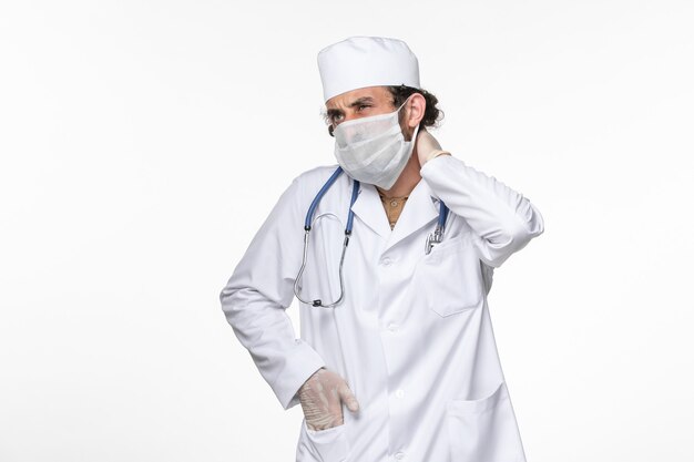 흰 벽 바이러스 코로나 바이러스 대유행 질병 질병에 목이 아픈 코비 드로부터 보호하기 위해 멸균 마스크를 착용 한 의료 소송에서 전면보기 남성 의사