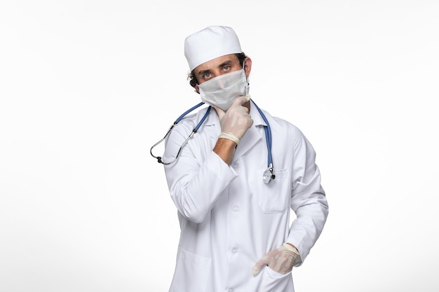白壁ウイルス病のcovid-pandemicに関するcovid-thinkingからの保護として滅菌マスクを着用した医療スーツの正面図男性医師