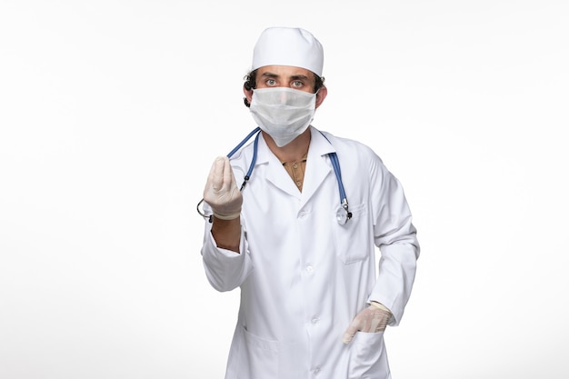 흰 벽 바이러스 코로나 바이러스 전염병에 대한 covid로부터 보호하기 위해 멸균 마스크를 착용하는 의료 소송에서 전면보기 남성 의사