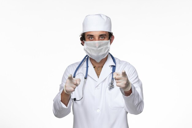 白壁ウイルス病のcovid-からの保護として滅菌マスクを身に着けている医療スーツの正面図男性医師covidパンデミック病