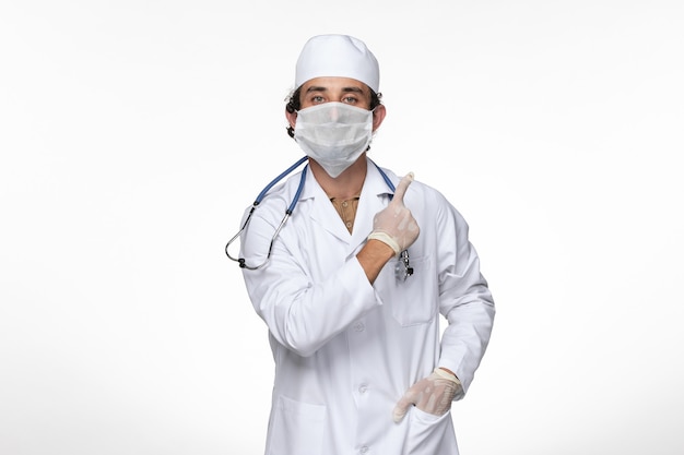 흰 벽 바이러스 질병 COVID 전염병에 대한 covid-로부터 보호하기 위해 멸균 마스크를 착용하는 의료 소송에서 전면보기 남성 의사