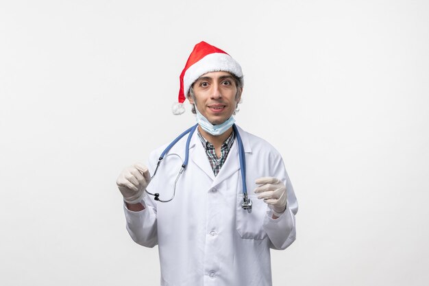 Front view male doctor in medical suit on a white wall virus holiday covid- emotion