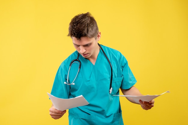 Front view of male doctor in medical suit with analysis on the yellow wall