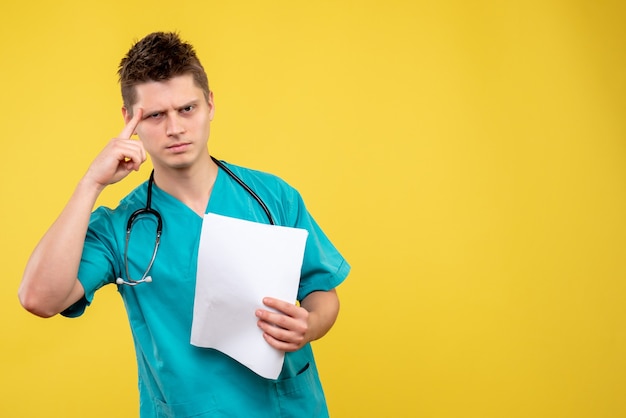Front view of male doctor in medical suit with analysis on yellow wall