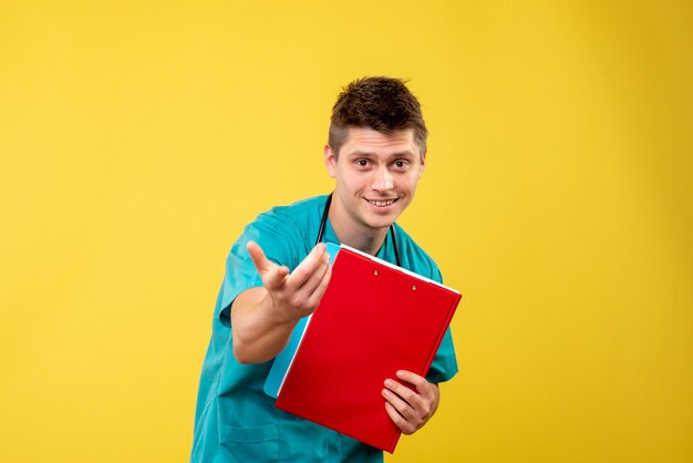 Front view of male doctor in medical suit with analysis on yellow wall