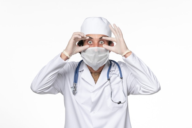 Free photo front view male doctor in medical suit with mask as a protection from covid- on light white wall coronavirus virus pandemic medicine