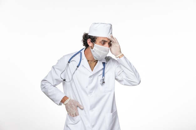 Вид спереди мужчина-врач в медицинском костюме с маской как защита от ковид-мышления на белой стене всплеск пандемии коронавируса