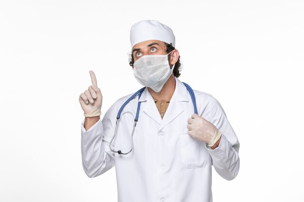 白壁ウイルススプラッシュコロナウイルスパンデミックからの保護としてマスク付きの医療スーツを着た正面図の男性医師